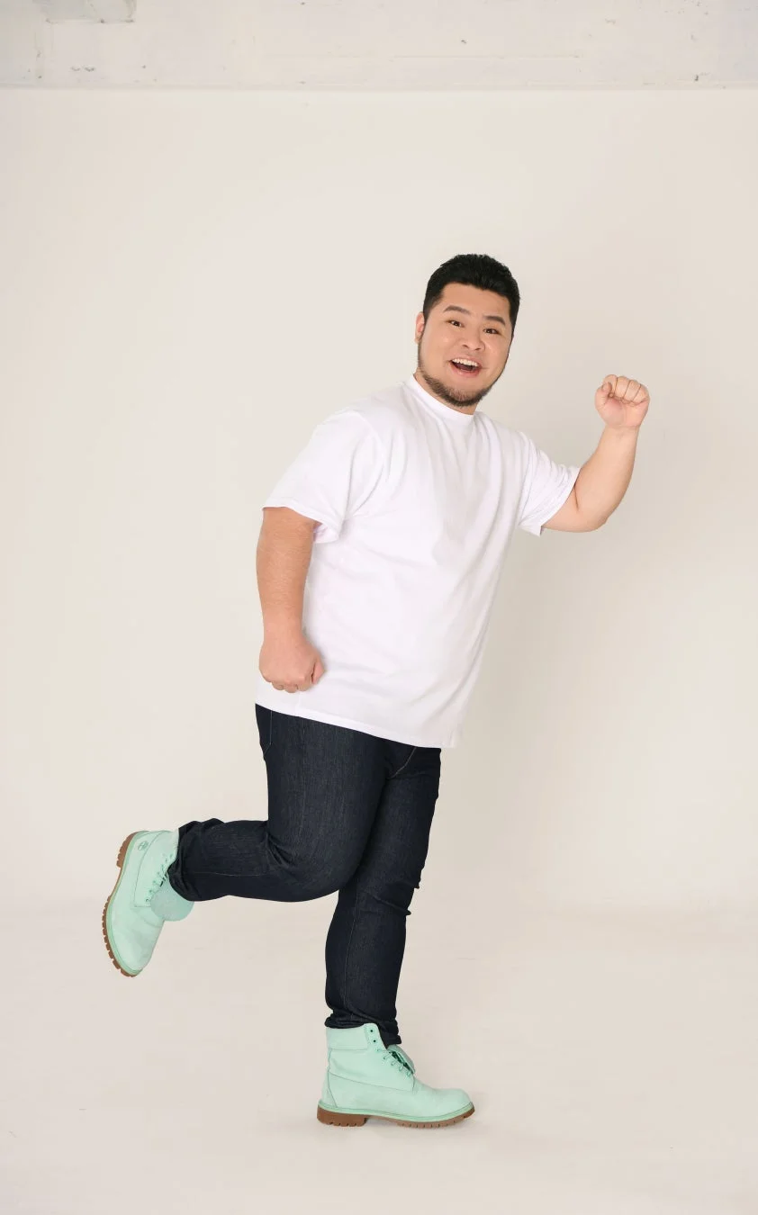 白Tシャツとジーンズの男性が笑顔でポーズをとっている全身写真