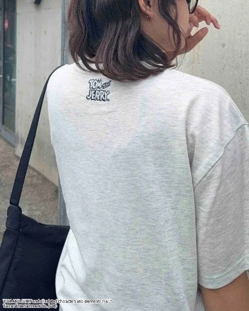 Person wearing a grey T-shirt with the Tom and Jerry logo on the back
