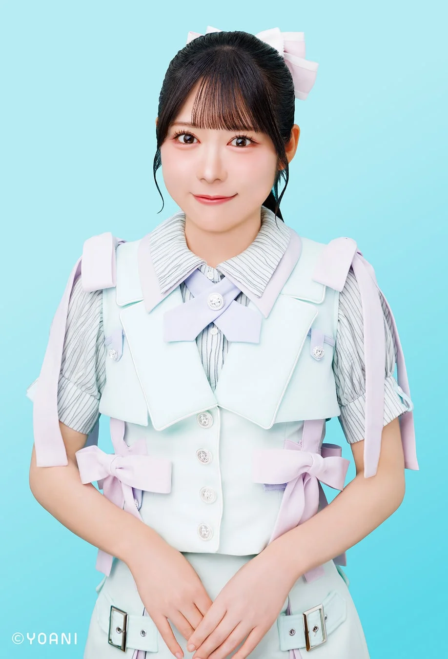 水色の背景を背に、パステルカラーの衣装を着た若い女性が優しく微笑む