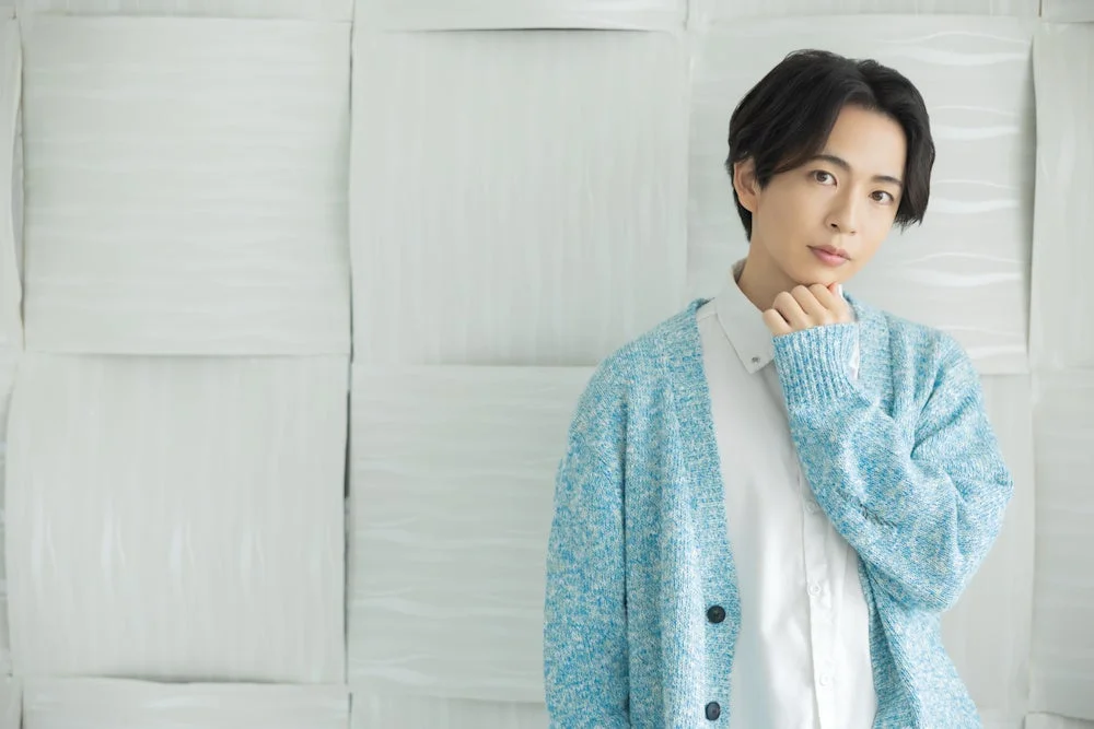 水色のカーディガンと白いシャツを着た若い男性のポートレート写真