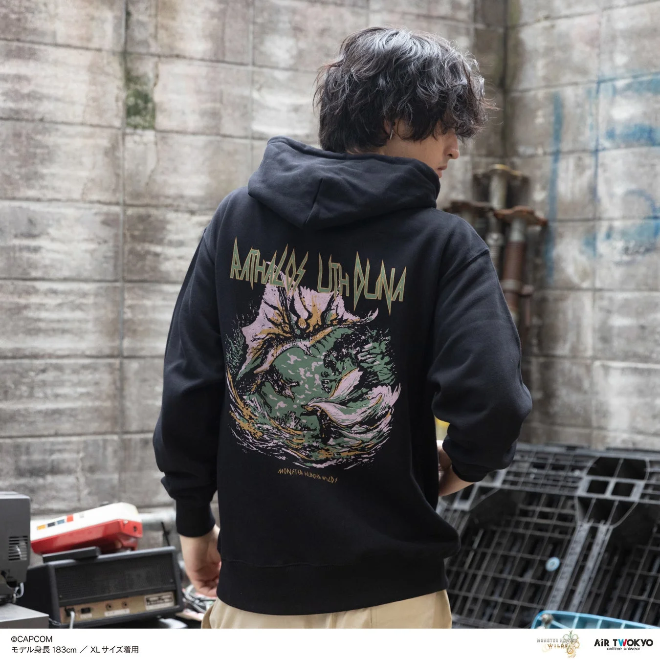 モンスターグラフィックが大胆に描かれた黒いパーカーを着用した男性モデルの後ろ姿