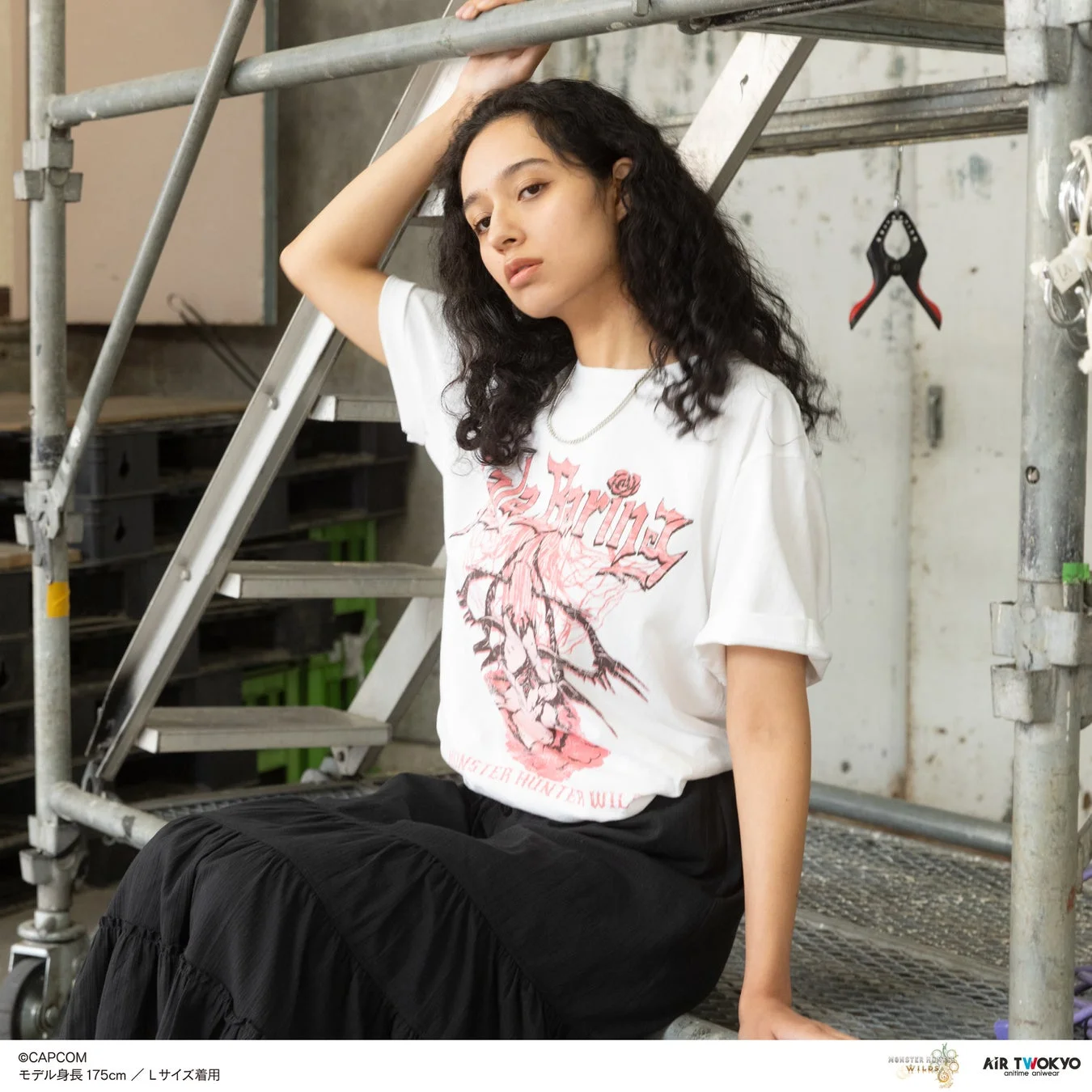 白いグラフィックTシャツと黒いロングスカートを着用した女性モデル