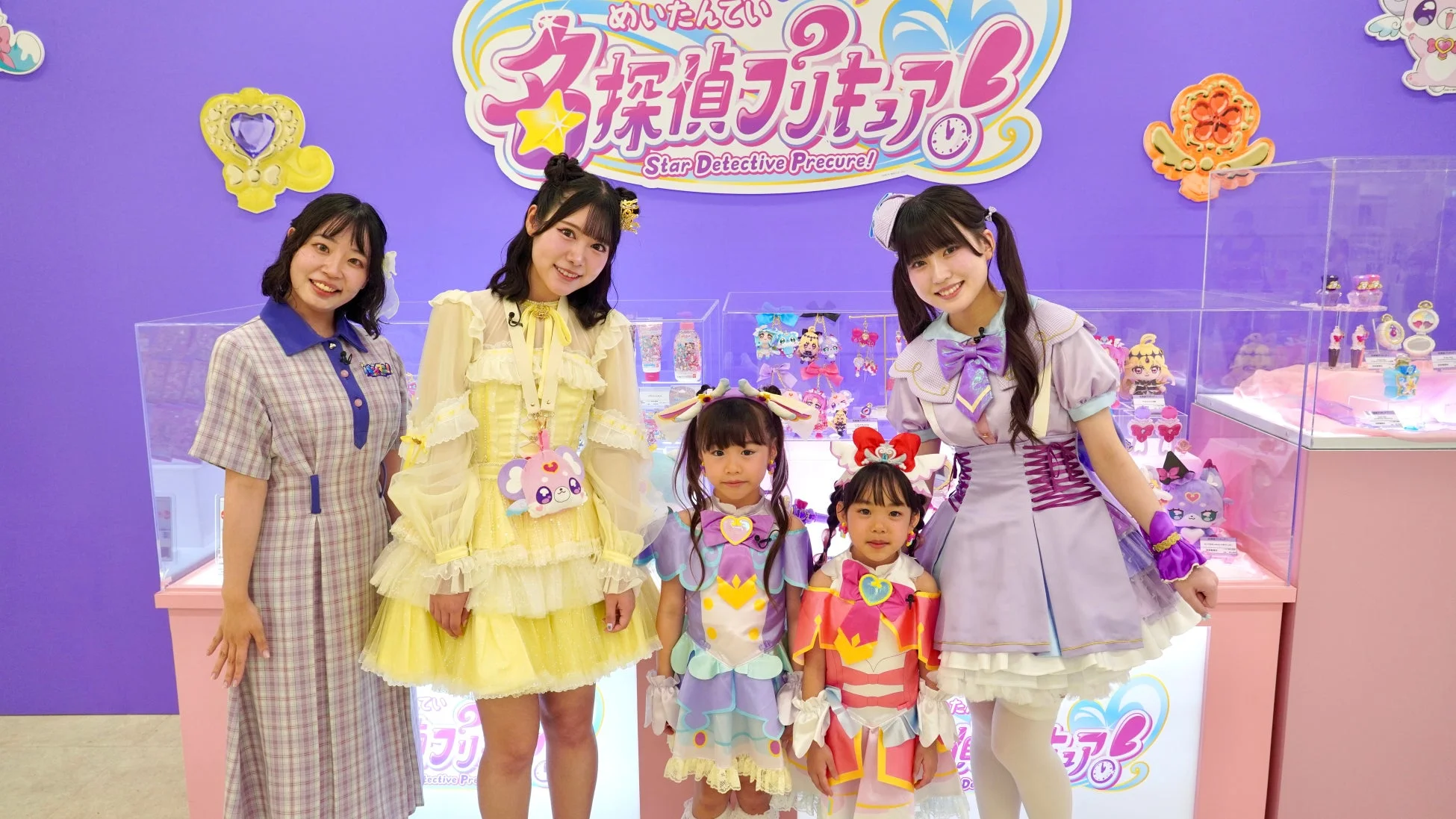 名探偵プリキュア」のイベント会場で、コスチュームを着た大人と少女がポーズをとる様子