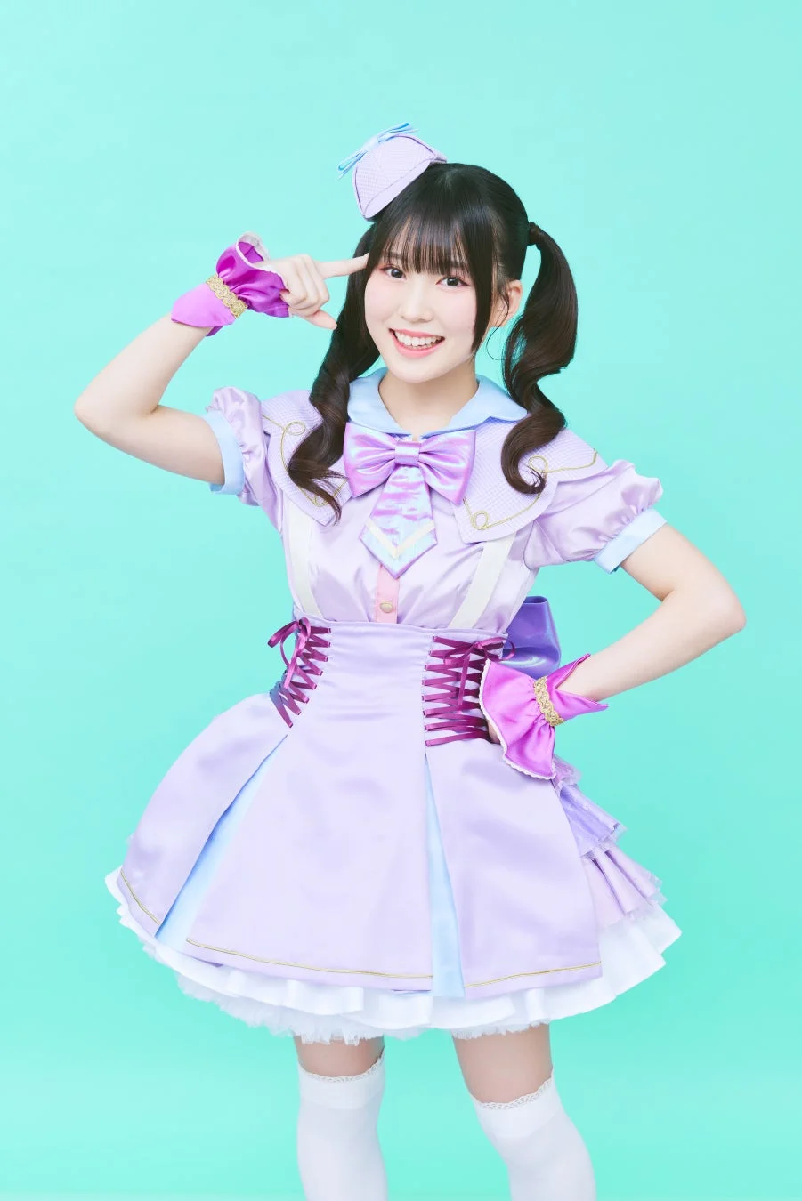 紫と水色のアイドル衣装を着用した若い女性が笑顔でポーズ