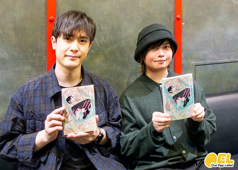 書籍を持って笑顔でポーズをとる2人の男性