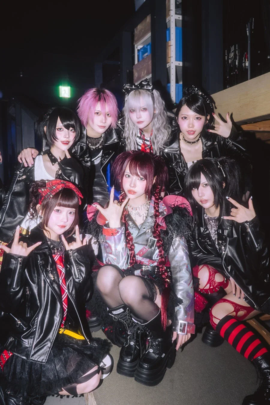 パンクやゴシックをテーマにした衣装をまとった7人の女性グループが、革ジャンと厚底ブーツ姿でポーズを決めています。