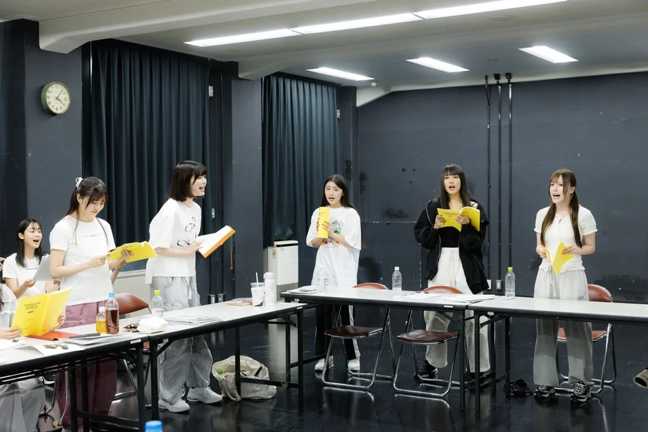 台本を手に歌唱練習をする女性グループ