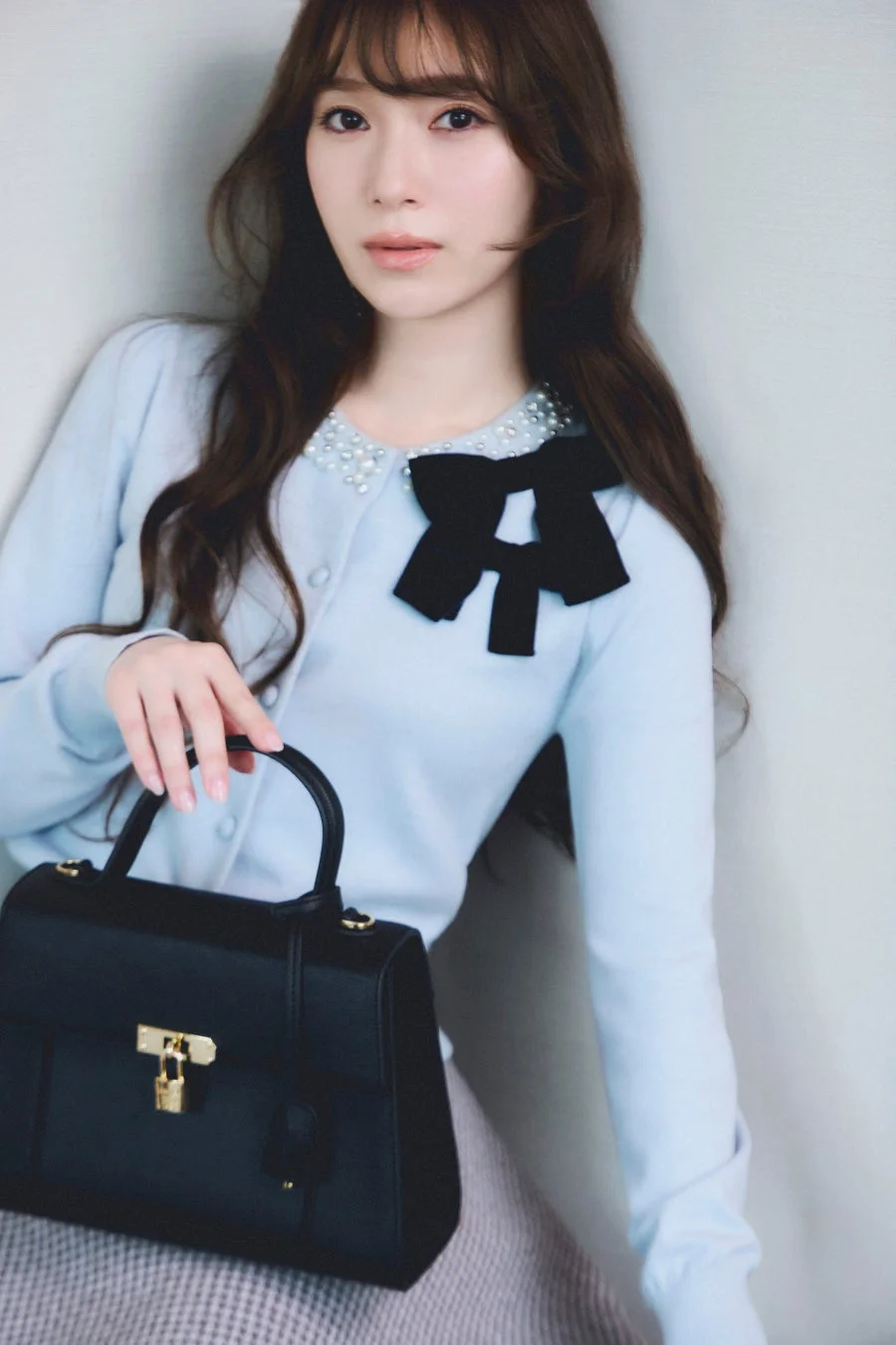 水色のカーディガンと黒いハンドバッグを持つ女性のポートレート