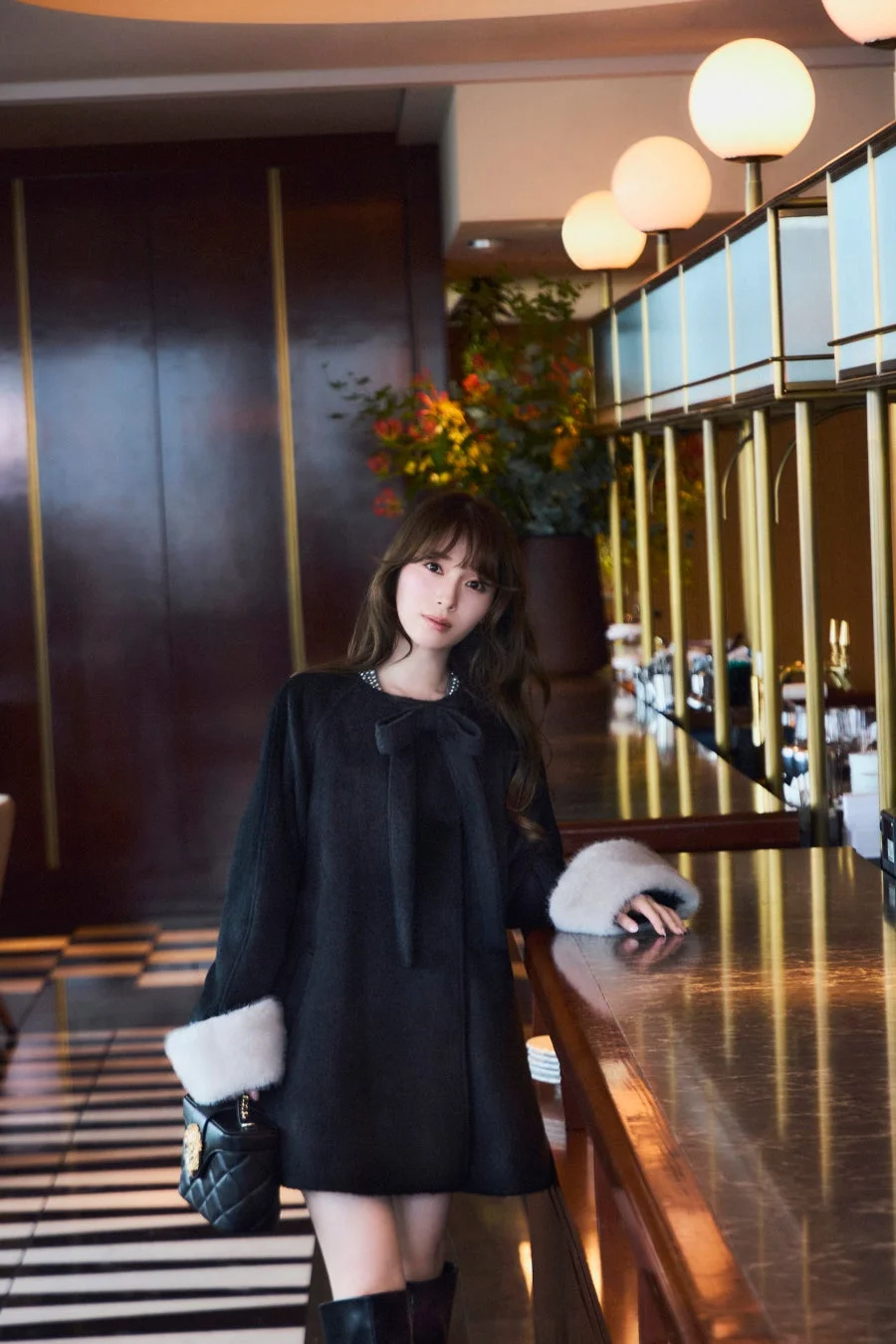 黒いコートにファーカフスとリボンが特徴的な服装のエレガントな女性
