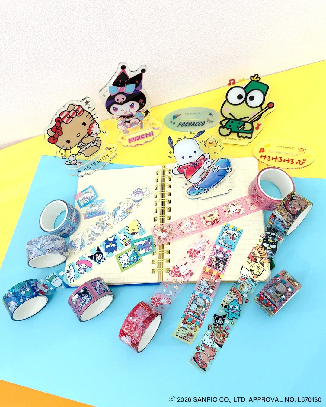 ハローキティ、クロミ、ポチャッコ、けろけろけろっぴといったサンリオキャラクターのマスキングテープやアクリルスタンドが並べられた画像です。カラフルで多様なデザインの文房具が、開かれたノートを中心に可愛らしく配置されています。